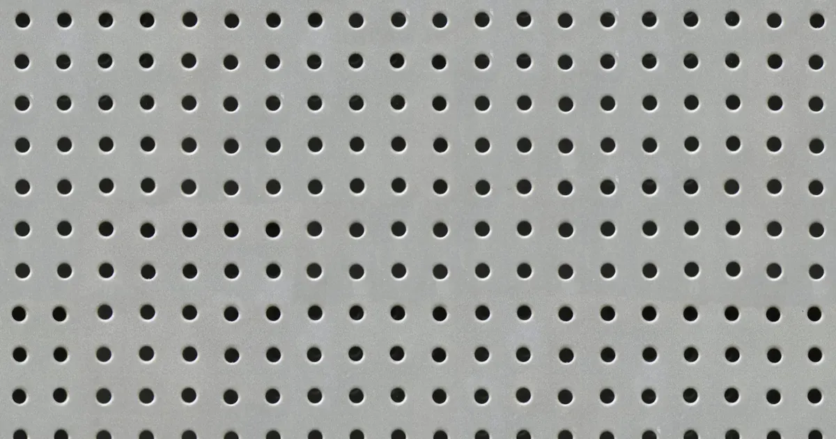 Flat metal plate with a regular grid of small round holes, the hole pattern behind showerhead machining